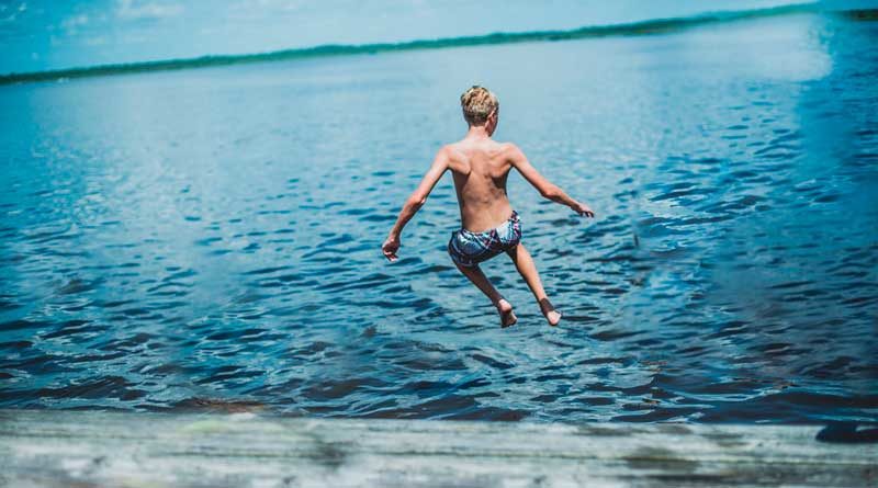 Junge springt in Badesee