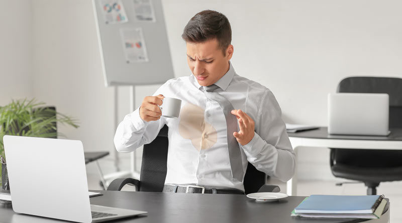 Businessmann verschüttet Kaffee auf sein weißes Hemd