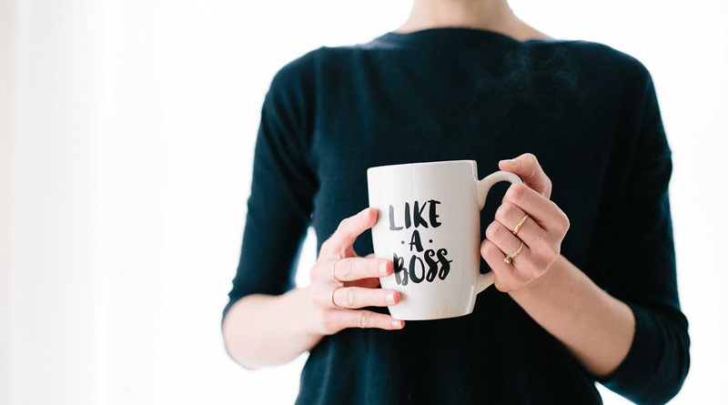 Frau hält Tasse mit Aufdruck in der Hand