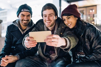 3 junge Leute machen lachend ein Selfie