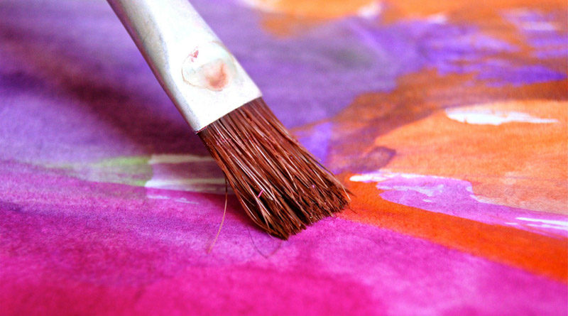 Nahaufnahme eines Malpinsels, der gerade Farbe auf ein Bild aufträgt