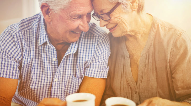 Älteres Ehepaar sitzt nebeneinander, halten Kaffeetassen