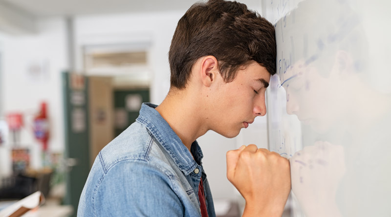 Schüler, der seine Stirn verzweifelt an die Tafel lehnt