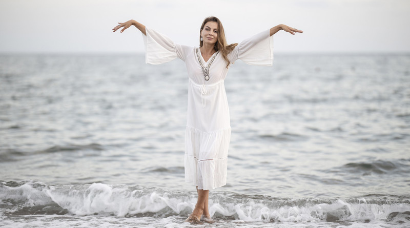 Frau im Sommerkleid steht im Meer