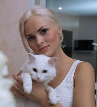 Junge Frau mit weiß-blondem Haar und einer weißen Katze auf dem Arm