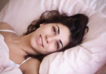 Entspannte, lächelnde Frau im Bett