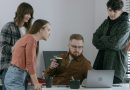 Vier Start-up-Mitarbeiter schauen auf das Display eines Laptops