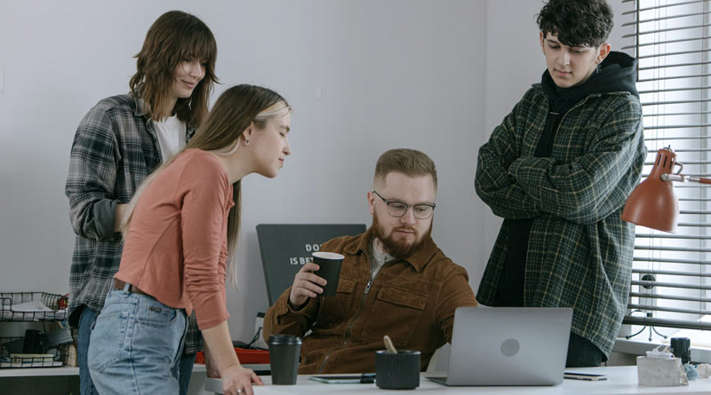 Vier Start-up-Mitarbeiter schauen auf das Display eines Laptops