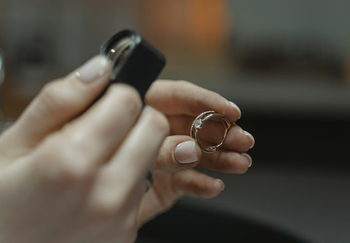 Juwelierin begutachtet Ring mit einer Lupe
