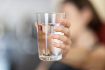 Hand einer Frau, die ein Glas Wasser hält