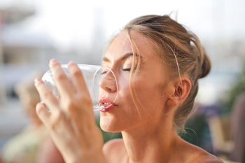 Frau trinkt Wasser aus einem Glas