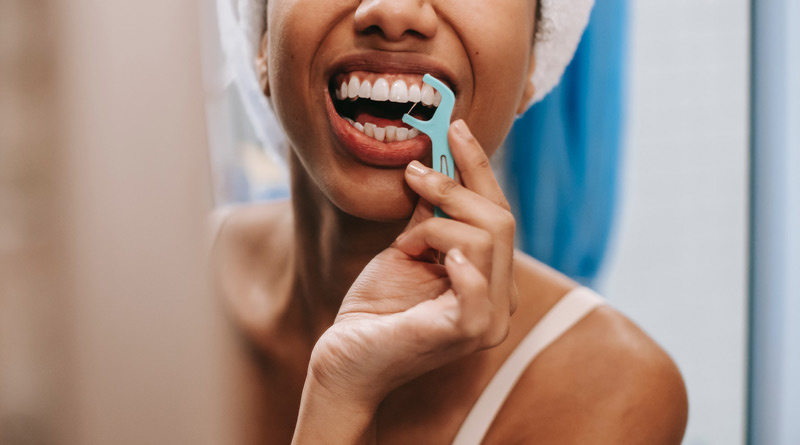 Frau, die ihre Zähne mit Zahnseide reinigt