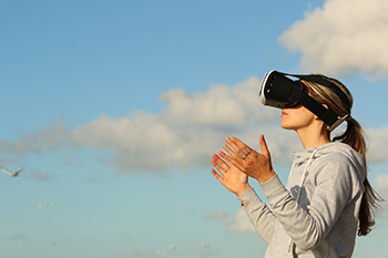 Frau mit VR Brille vor einem Himmel mit Wolken