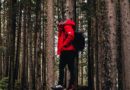 Mann in roter Regenjacke wandert durch den Wald
