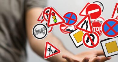 Eine Hand, die viele verschiedene Verkehrsschilder scheinbar jongliert.