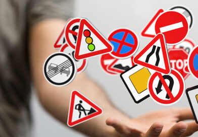 Eine Hand, die viele verschiedene Verkehrsschilder scheinbar jongliert.