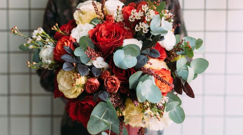 Ausschnitt einer Frau, die einen üppigen Blumenstrauß in den Händen hält.
