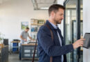 Mitarbeiter erfasst seinen Arbeitsbeginn an einer digitalen Stempeluhr