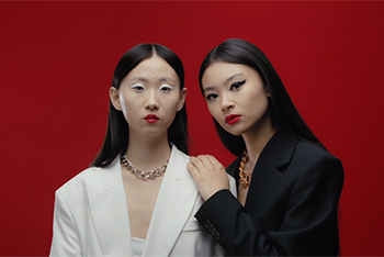 Zwei Frauen, eine in Weiß mit Silberschmuck, eine in Schwarz mit Goldschmuck