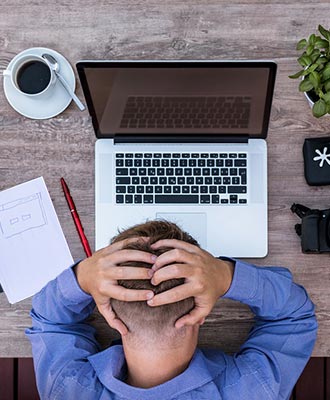 Junger Mann sitzt verzweifelt an seinem Laptop