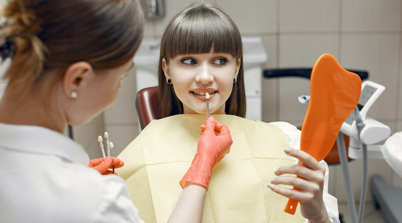 Junge Frau, die bei einer Zahnärztin die Farbe ihrer Veneers aussucht