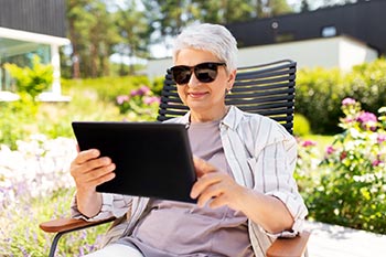 Ältere Frau liest ein eBook mit einer Blaulichtfilterbrille