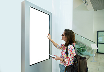 Mitarbeiterin informiert sich an einem Digital Signage Display