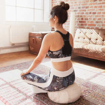 Frau sitzt auf Yogakissen