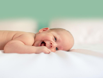 Lachendes Baby liegt auf einer Decke