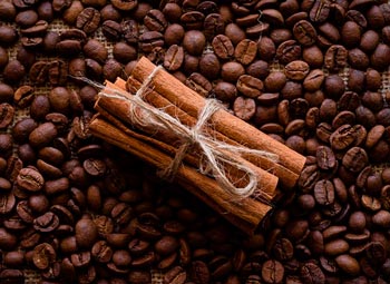 Zimtstangen, die auf Kaffeebohnen liegen