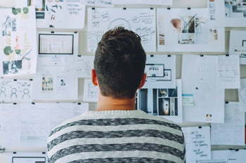 Mann steht vor Board mit Charts und Diagrammen